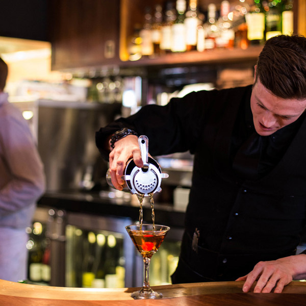Bartender straining a Manhattan